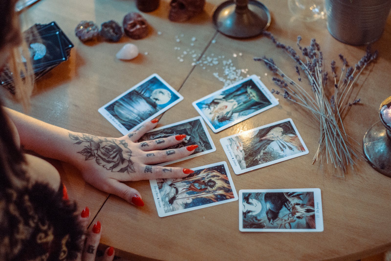 Fortune teller with tattoos on her hand and tarot cards on the table.